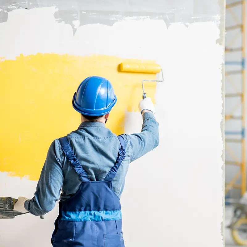 Maler streicht gelbe Wand